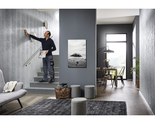 Scène d''une cage d''escalier au design moderne avec une personne touchant un mur, des meubles et des décorations