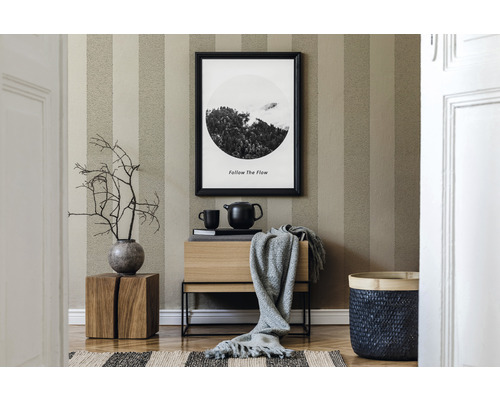 Wohnraum mit gestreifter Tapete, Holzkommode, Dekoration und geflochtenem Korb