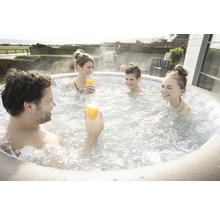 Famille avec des boissons se détendant dans un jacuzzi gonflable à l''extérieur.