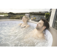 Un couple se détend dans un jacuzzi gonflable à l''extérieur.
