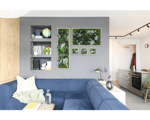 Wohnzimmer mit blauem Sofa und Wanddekoration aus Pflanzenbildern