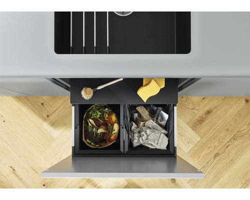 Ansicht von oben eines Abfalltrennbehälters mit zwei Fächern unter einer Spüle, gefüllt mit Biomüll und Altpapier.