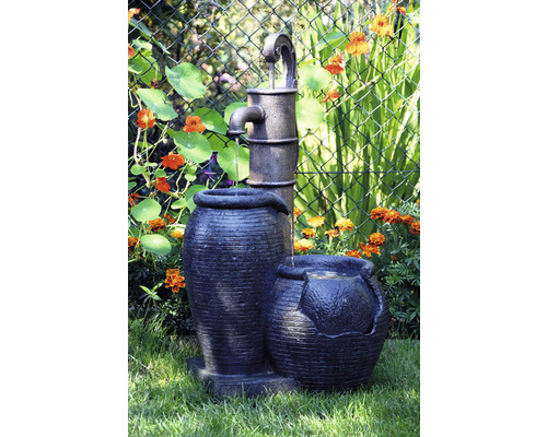 Fontaine de jardin avec pompe à eau et pots de fleurs dans le jardin