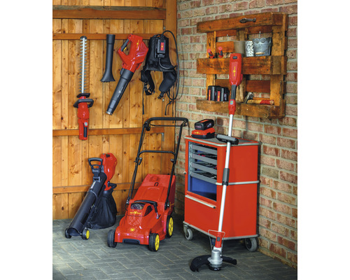 Gartengeräte wie Rasenmäher, Heckenschere und Laubbläser in einer Garage