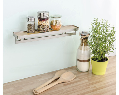 Wandregal mit Gewürzgläsern, Holzlöffeln und Kräutertopf auf einer Küchentheke.