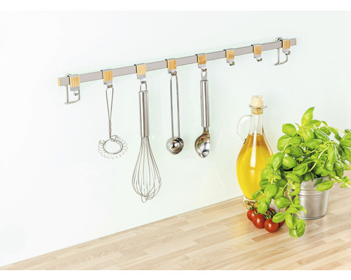 Küchenutensilien hängen an einer Küchenreling mit Haken an der Wand.