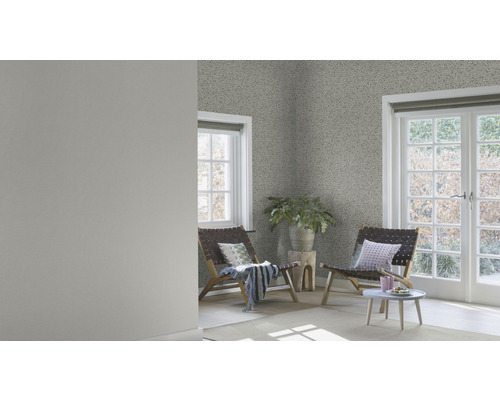 Pièce lumineuse avec papier peint à motifs, deux chaises en bois et une petite table