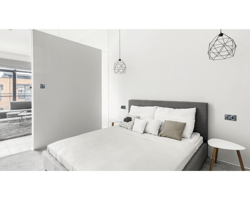 Schlafzimmer mit Bett, Nachttischen und geometrischen Lampen