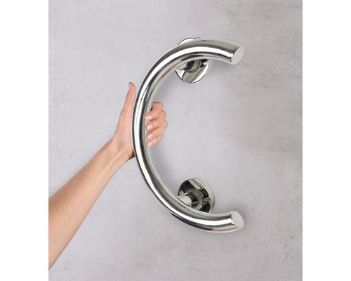 Person hält einen gebogenen Haltegriff aus Edelstahl an der Wand.