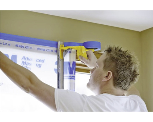 Homme utilisant du ruban de masquage et un film de protection pour recouvrir un cadre de fenêtre