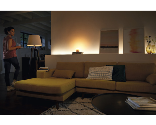 Wohnzimmer mit Sofa, Tischlampe und indirekter Beleuchtung für eine gemütliche Atmosphäre