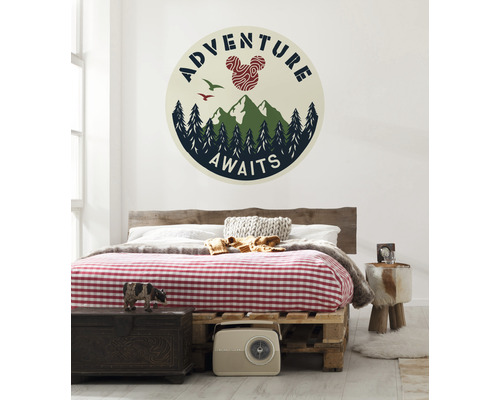 Décoration murale avec un sticker mural représentant des montagnes, des arbres, des oiseaux et le texte l''aventure vous attend au-dessus d''un lit