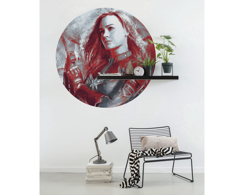Décoration murale avec motif Captain Marvel au-dessus d''une étagère avec des objets de décoration, une lampe et une chaise dans la pièce.