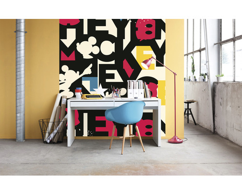 Une pièce avec un bureau, une chaise et un papier peint avec un motif de lettres