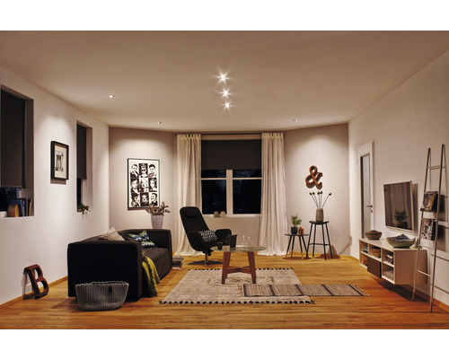 Salon avec canapé, fauteuil, table basse et plafonniers pour une ambiance lumineuse