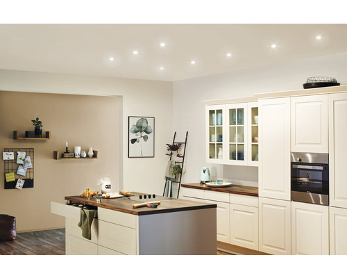 Cuisine claire avec îlot de cuisine, armoires encastrées et spots de plafond.