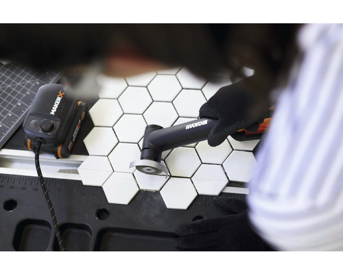 Coupe-carreaux coupant des carreaux hexagonaux sur un établi, alimenté par le concentrateur Maker X et le logo Worx.