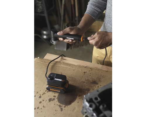 Une personne connecte une meuleuse d''angle sans fil à une batterie de 20 volts sur un établi.