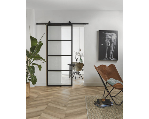 Salon avec porte coulissante en verre à cadre noir, plancher en bois et décoration