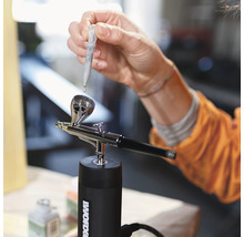 Person befüllt Airbrushpistole mit Pipette