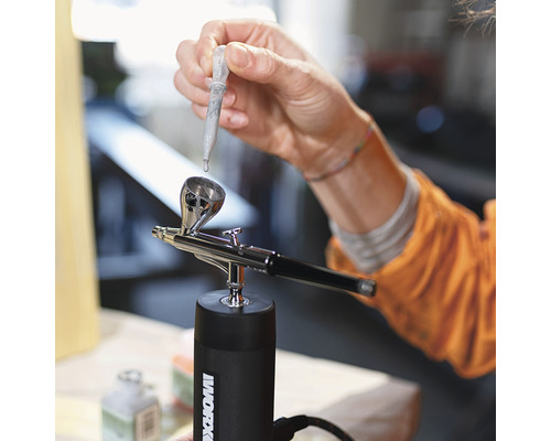 Personne remplissant un aérographe avec une pipette