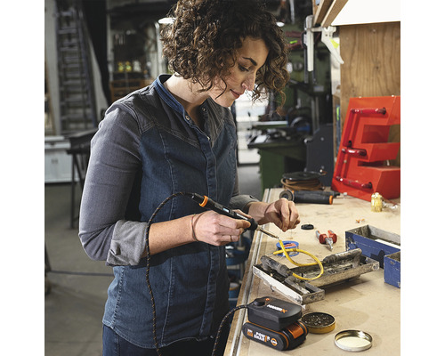 Frau lötet mit Lötkolben in Werkstatt.