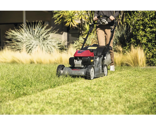 Eine Person bedient einen Rasenmäher im Garten.