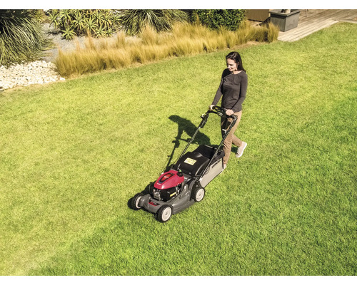 Frau bedient Rasenmäher auf Rasenfläche