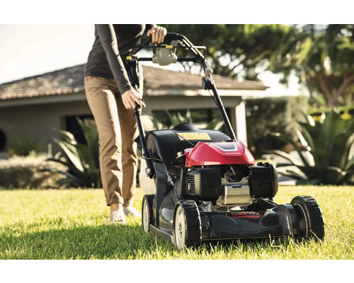 Eine Person bedient einen Rasenmäher im Garten.