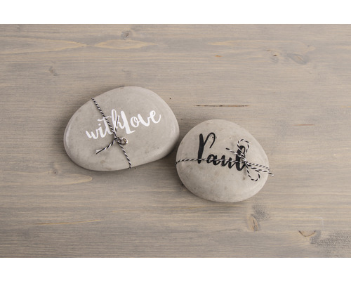 Zwei beschriftete Steine mit Kordel auf einem Holztisch.