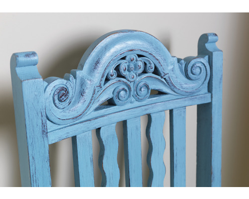 Vue détaillée du dossier d''une chaise en bois bleu clair avec des sculptures décoratives