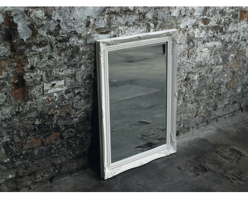 Miroir rectangulaire avec cadre décoré appuyé contre un mur