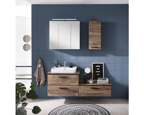Salle de bains lumineuse avec meuble-lavabo, armoire de toilette et armoire haute décor bois devant un mur bleu.