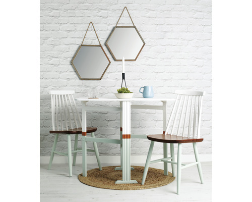 Salle à manger avec table, chaises et deux miroirs hexagonaux au mur