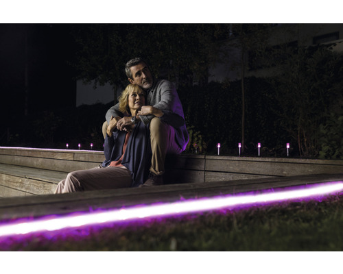 Ein Paar sitzt abends auf einer beleuchteten Gartentreppe, wobei die Gartenbeleuchtung eine stimmungsvolle Atmosphäre erzeugt.