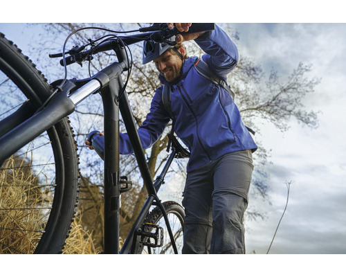 Un homme pousse un VTT noir en haut d''une colline