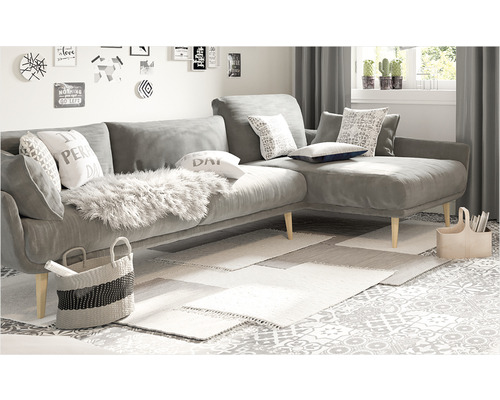 Wohnzimmer mit grauer Eckcouch, Kissen, Teppichen und Dekorationsgegenständen.