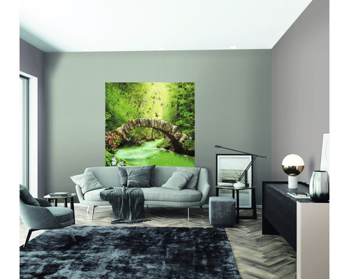 Salon avec canapé, fauteuil, tapis et une peinture murale représentant un pont de pierre dans une forêt