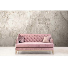 Rosa Sofa mit zwei Kissen vor einer Wandtapete mit Marmormuster.