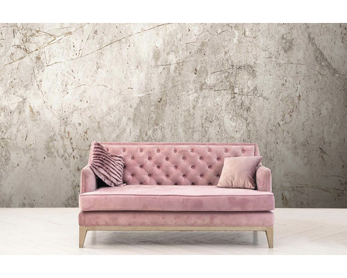 Canapé rose avec deux coussins devant un papier peint à motif de marbre.