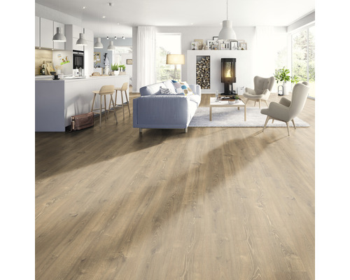Espace de vie lumineux avec plancher en bois, canapé, fauteuils et cheminée.