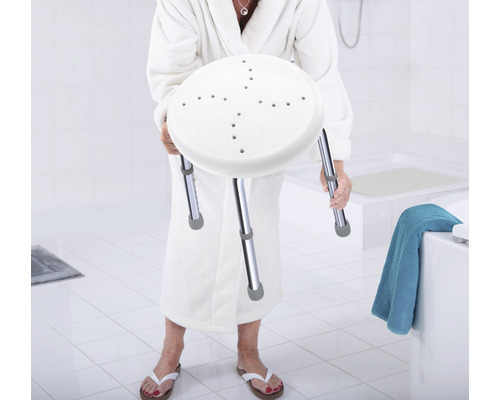Femme en peignoir tenant un tabouret de douche avec des pieds réglables en hauteur