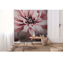 Salon avec papier peint à fleurs, fauteuil en rotin, table en bois et tapis en jute pour une ambiance naturelle.