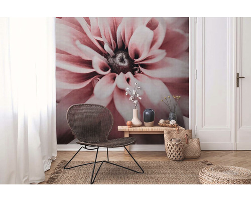 Salon avec papier peint à fleurs, fauteuil en rotin, table en bois et tapis en jute pour une ambiance naturelle.