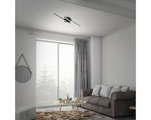 Wohnzimmer mit Deckenleuchte, Sofa, Vorhang und Fenster.