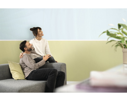 Paar sitzt auf Sofa vor gestrichener Wand im Wohnzimmer