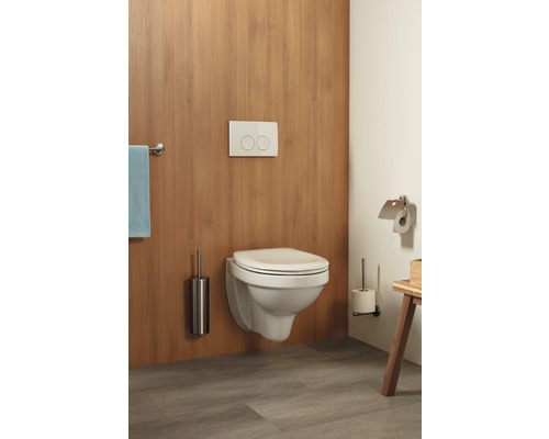 Wandhängendes WC mit Betätigungsplatte, Toilettenbürste und Toilettenpapierhalter in einem Badezimmer.