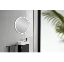 Badezimmer mit rundem Spiegel und LED-Beleuchtung über einem Waschbecken