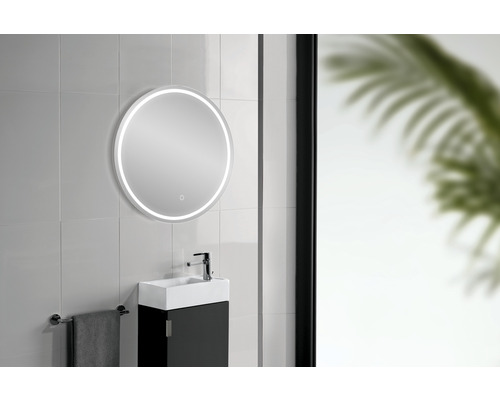 Salle de bains avec miroir rond et éclairage LED au-dessus d''un lavabo