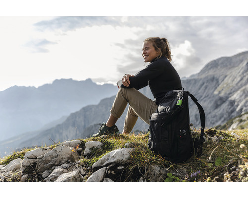 Femme avec sac à dos assise dans les montagnes et profitant de la vue